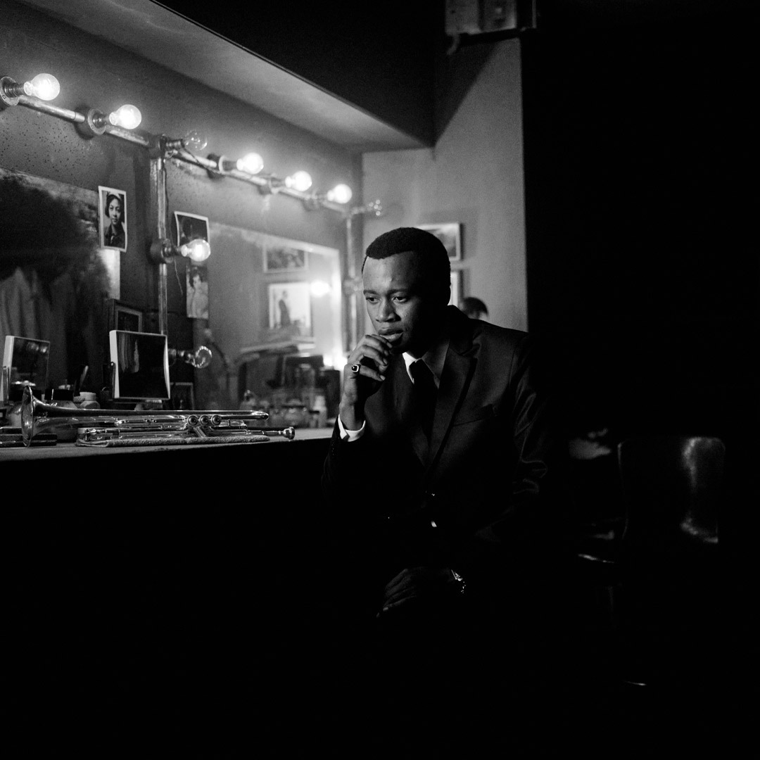 Grayscale photo of same musician sitting beside mirror