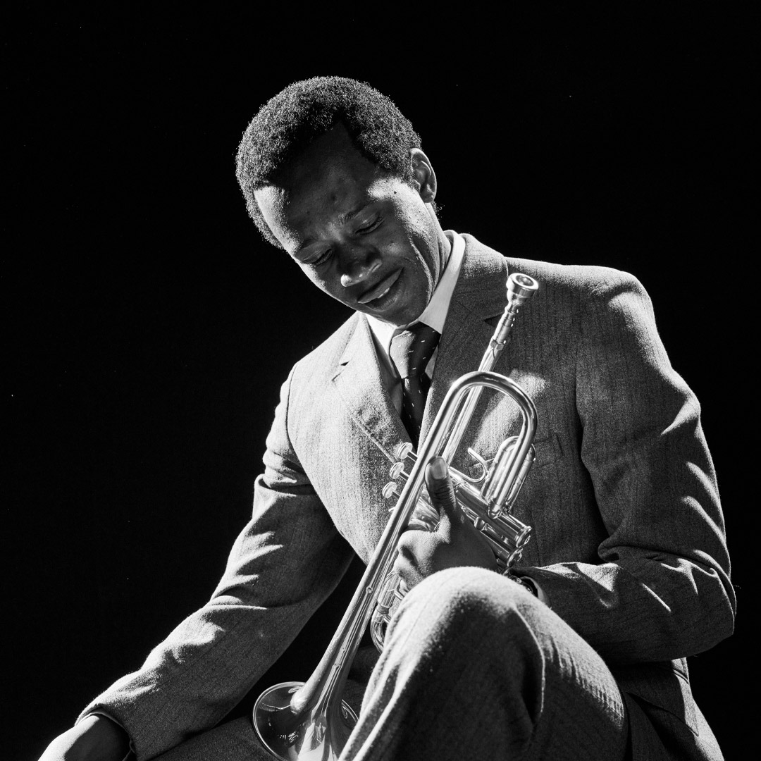 Grayscale photo of same musician holding trumpet