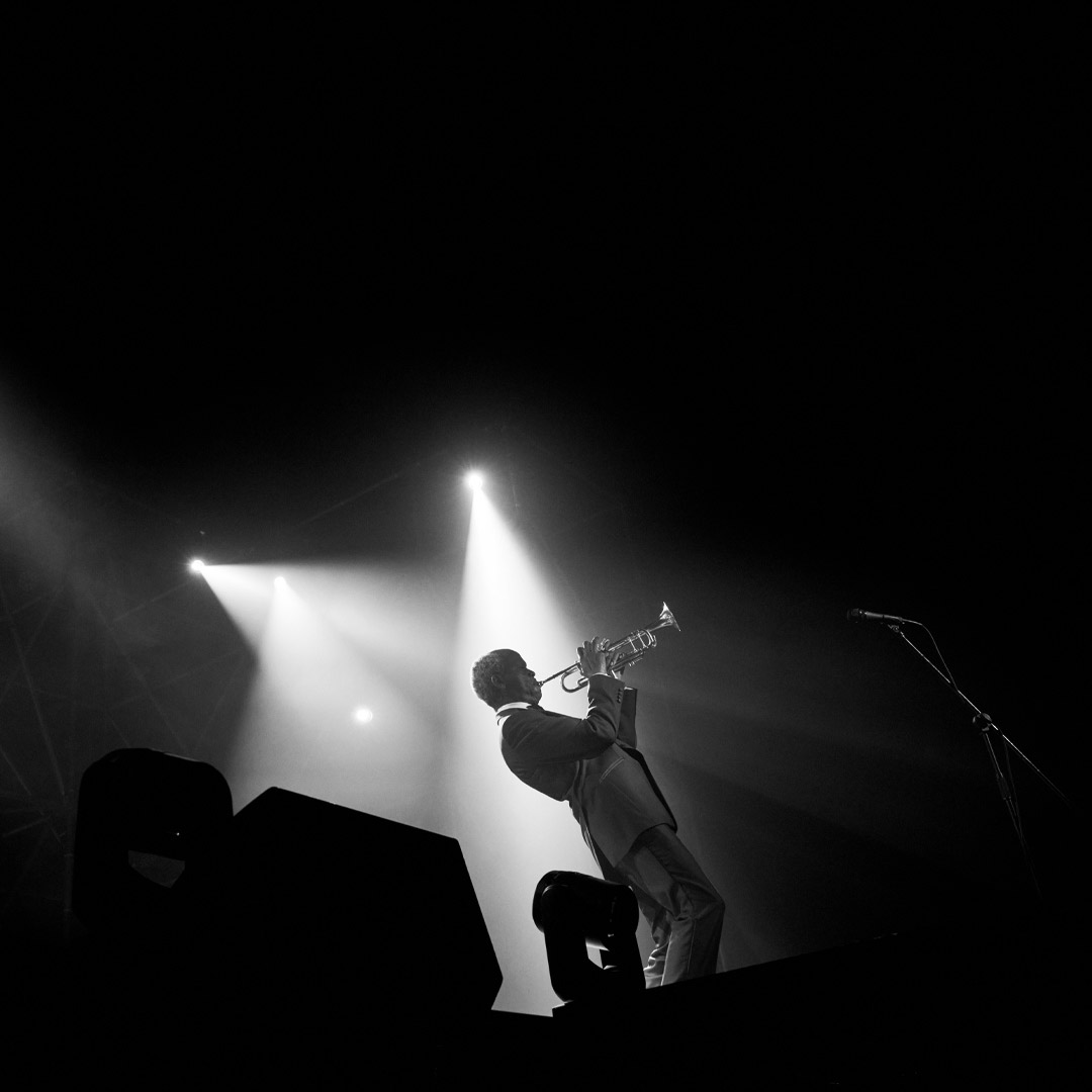 Grayscale photo of same older musician performing on stage